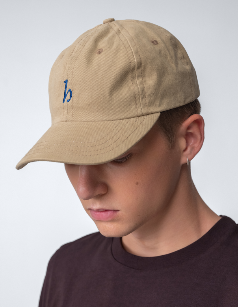 Hanover Cap in cotton twill worn by a young man, showcasing unstructured design and logo embroidery.