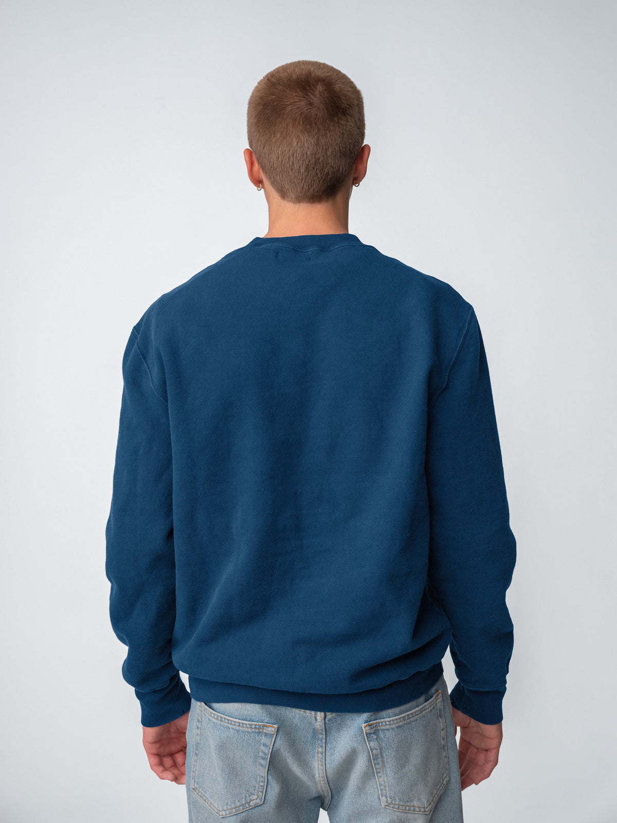 Guy wearing Sunwashed Staple Crewneck in mid navy back view