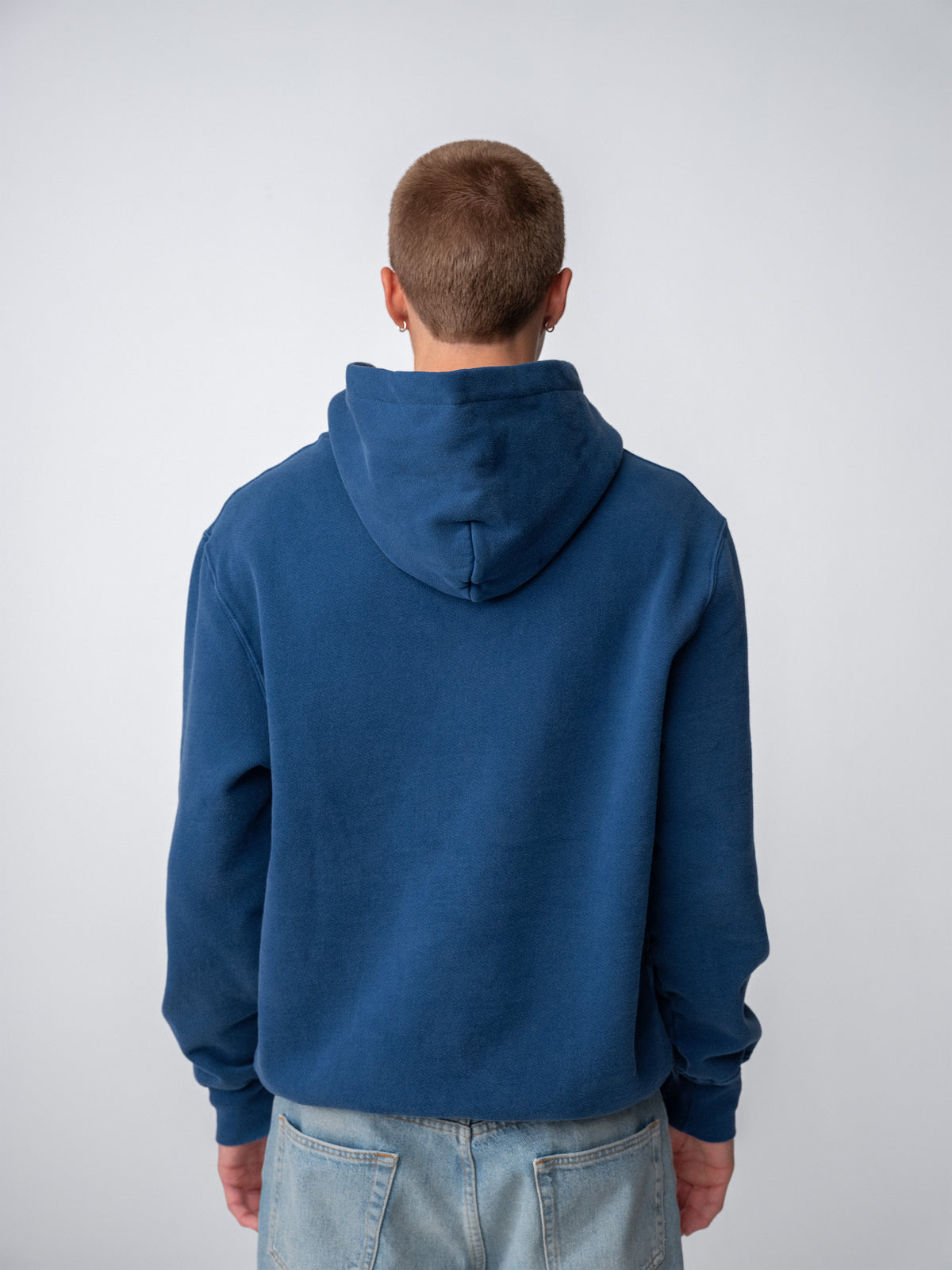Model wearing Sunwashed Staple Hoodie in mid navy back view