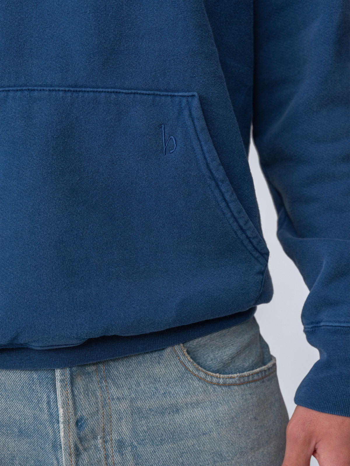 Model wearing Sunwashed Staple Hoodie in mid navy close up detail