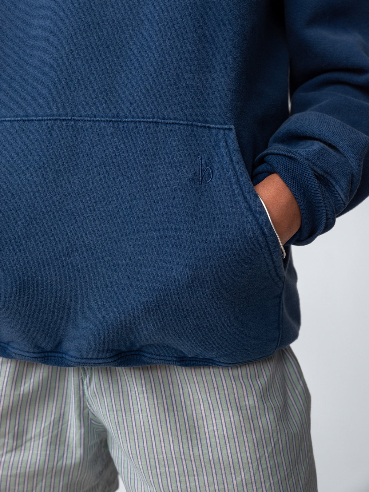 Woman model wearing Sunwashed Staple Hoodie in mid navy embroidery detail