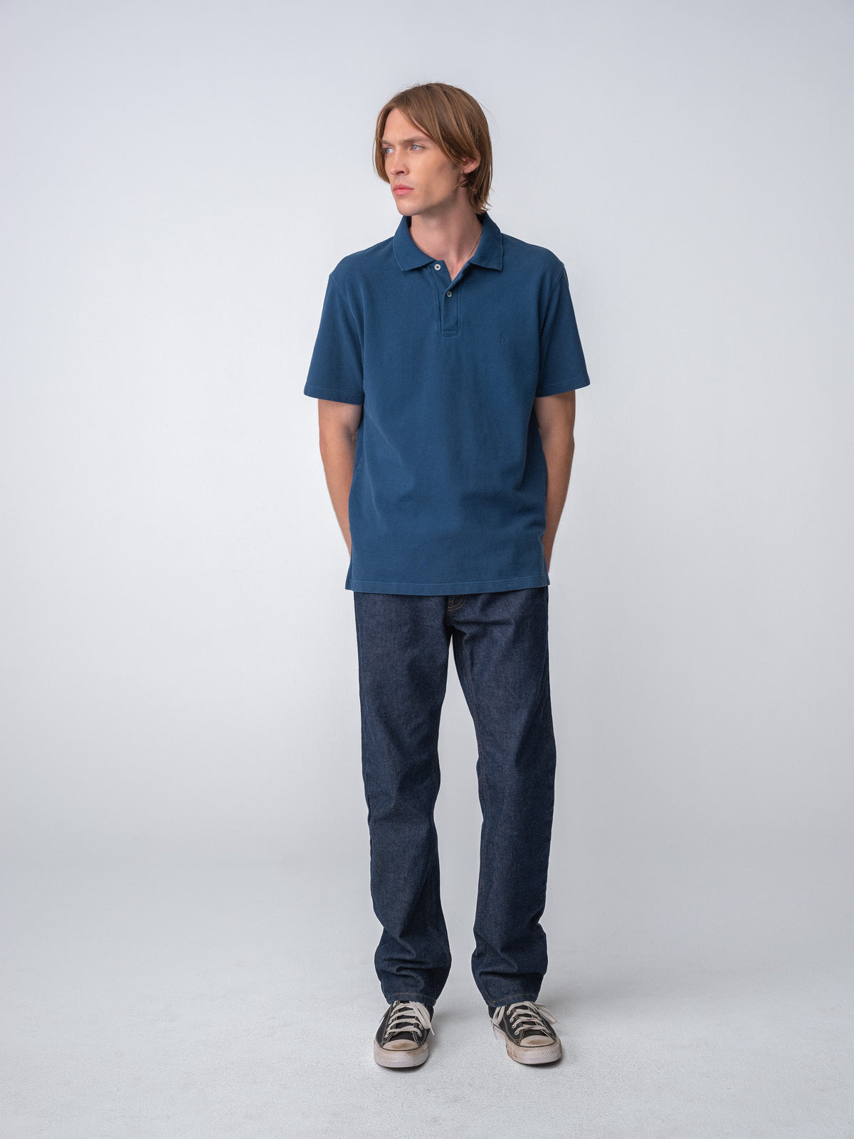 Model wearing a Sunwashed Staple Polo Shirt in mid navy color, full body