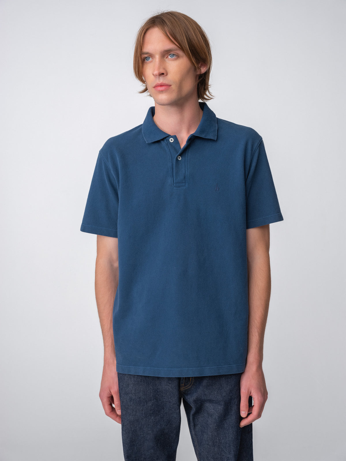 Model wearing a Sunwashed Staple Polo Shirt in mid navy color, torso shot body