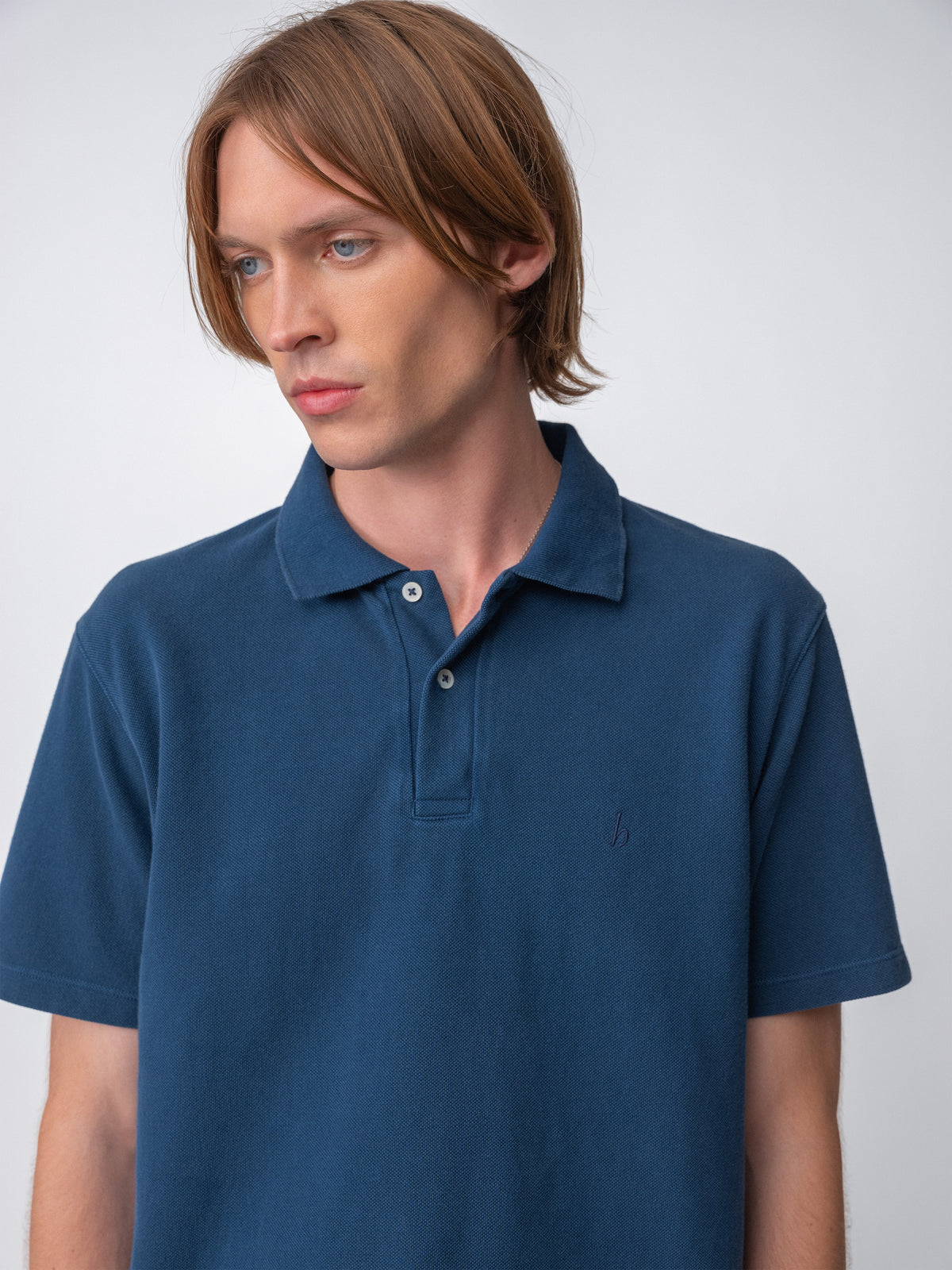 Model wearing a Sunwashed Staple Polo Shirt in mid navy color, featuring a classic collar and short sleeves. back view