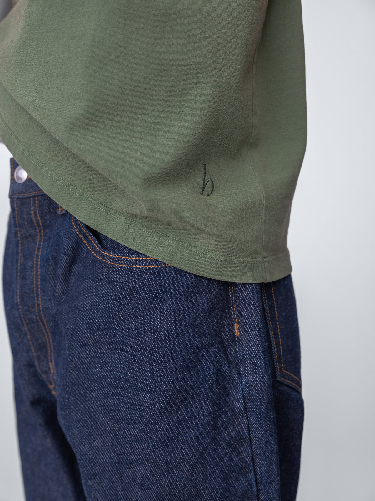 Model wearing Sunwashed Staple T-Shirt in spruce detail view