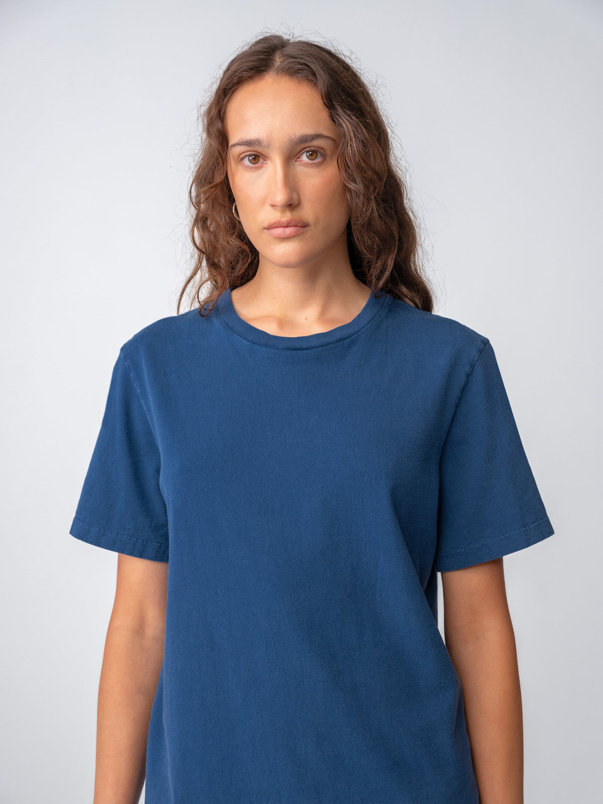 Model female wearing Sunwashed Staple T-Shirt in mid navy torso view
