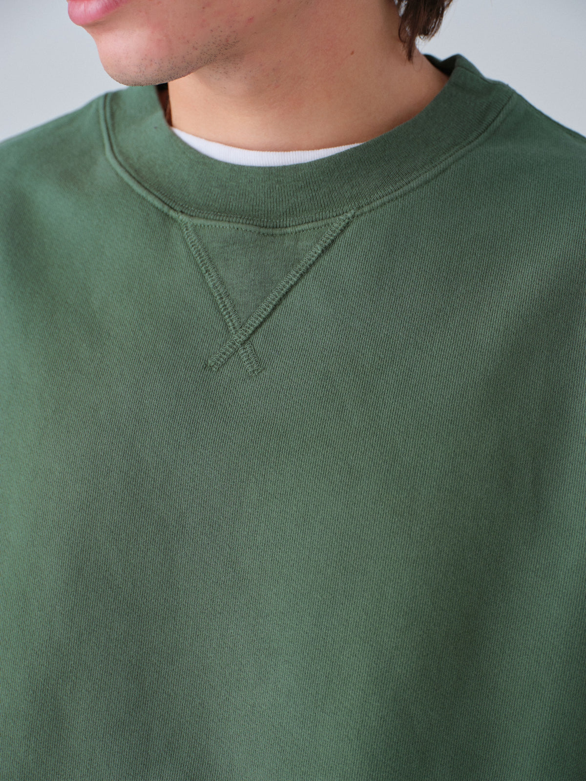 Detail of guy wearing Sunwashed Staple Crewneck in hunter green
